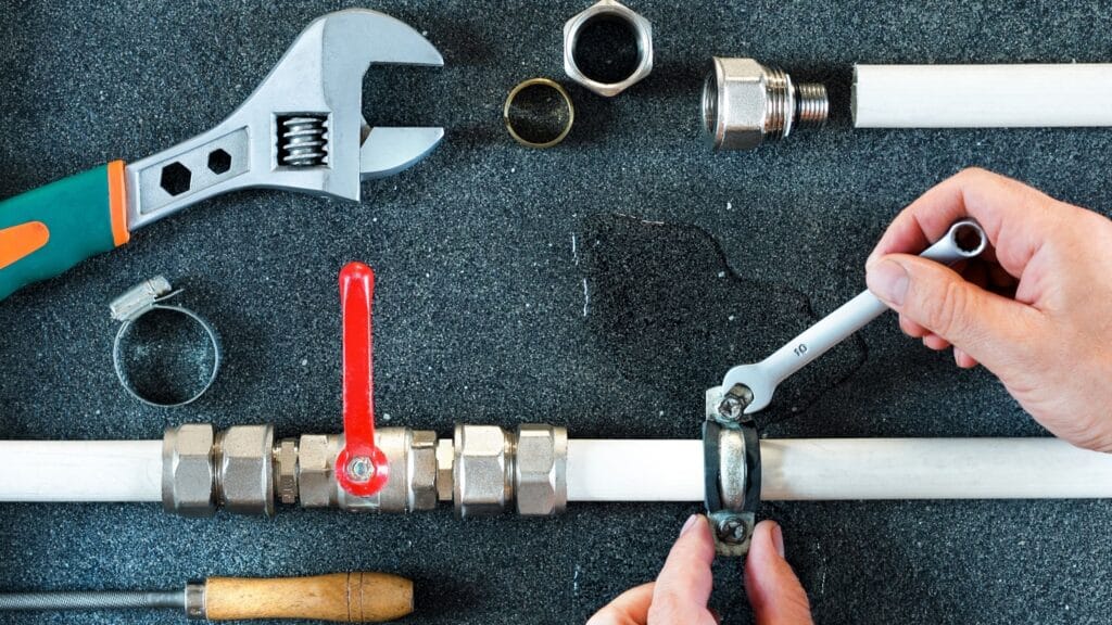 Plumber repairing a pipe valve with an adjustable wrench in Palm Bay