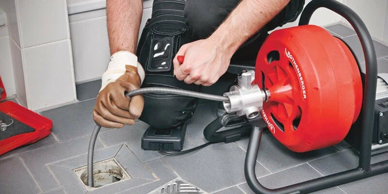 Plumber using a drain-cleaning machine in Palm Bay