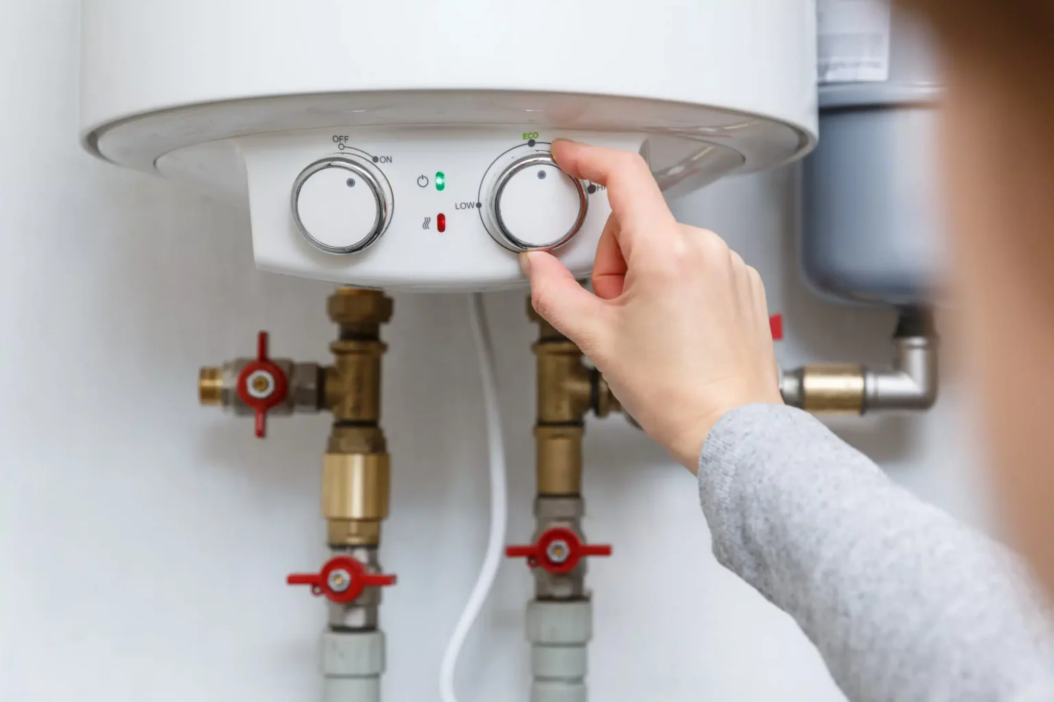 Homeowner adjusting the temperature controls on a water heater in Palm Bay